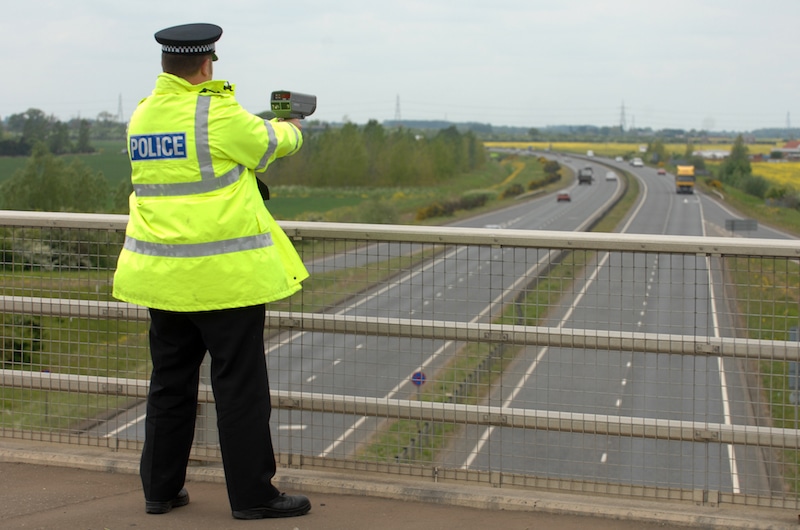 A British Police officer operating a hand held speed gun